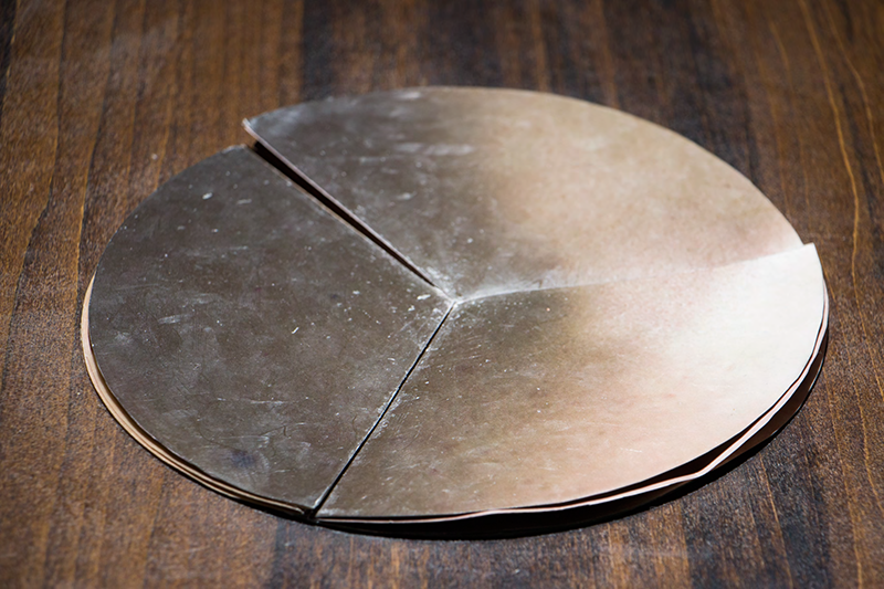 Circuler non-linear artist book with flesh imagery on a wooden table.